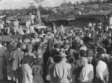 Soap box derby prize-giving. Onlookers crowd eagerly around child participants at the prize-giving