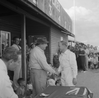 Handshake at the Nakuru Races. A man in white overalls shakes hands as he receives an award at a