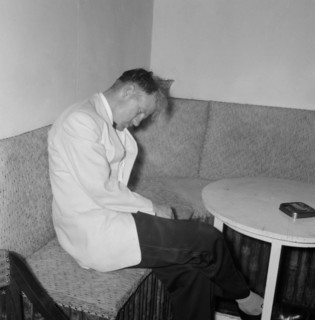 Worse for wear. A formally dressed man looks the worse for wear as he nods off in corner during a