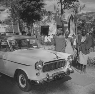 Maasai at Cooper Motors. Three Maasai warriors stand, holding spears, beside a shiny new car on