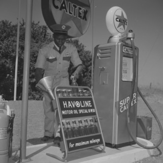 Havoline at Caltex. A uniformed attendant holds a funnel in one hand and a bottle of 'Havoline