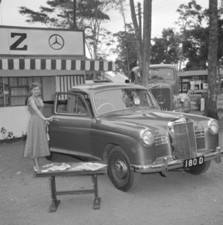 D.T. Dobie stand. A woman poses for the camera, opening the door of a new Mercedes car on display