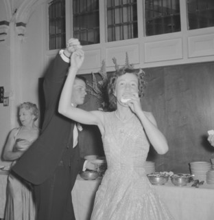 Dancing at the Limuru Hunt Ball. A young woman dressed in evening wear eats with one hand as she is