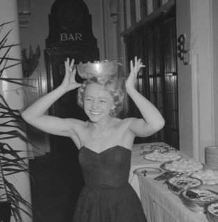 A well balanced diet. A woman dressed in an evening gown and jewellery attempts to balance a bowl