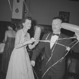 Single balloon salute. A middle-aged man at a Northern Counties dance, salutes the camera with a