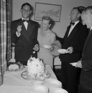 Cutting the cake. A young man dressed in a tuxedo, holds up a knife for the camera before cutting