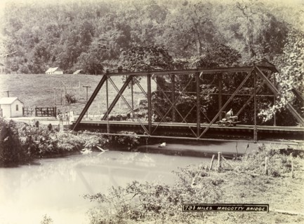 Railway track over Maggotty Bridge. A man operating a hand cart travels across a metal railway