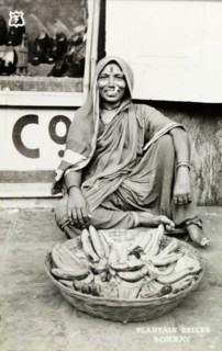 Plantain seller, Bombay. A smiling woman sells plantains from a basket on a city street. Bombay