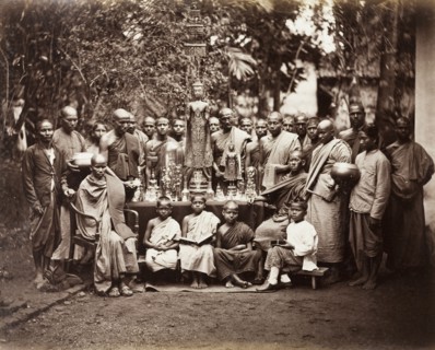 Buddhist monks with religious icons. A group of Buddhist monks stand around a table laden with
