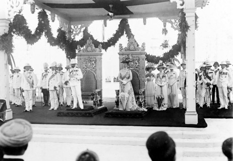 King George V arrives in Bombay. King George V (r.1910-36) and Queen Mary stand before a pair of
