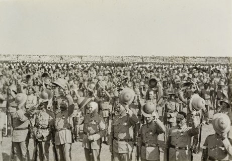 Three cheers for King George V. Numerous lines of uniformed soldiers stretch into the distance,
