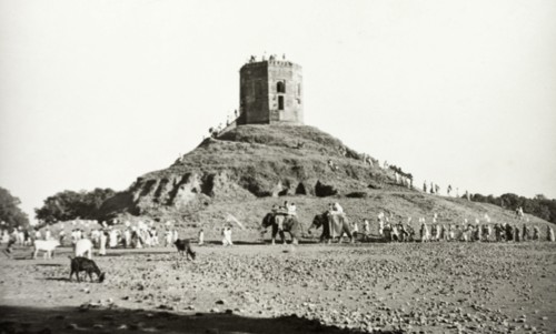 Monument near Benares. A long line of people, some riding elephants, visit an unidentified monument