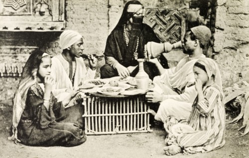 A familiar dinner'. A posed portrait depicting a 'typical' Egyptian meal. A veiled woman adorned
