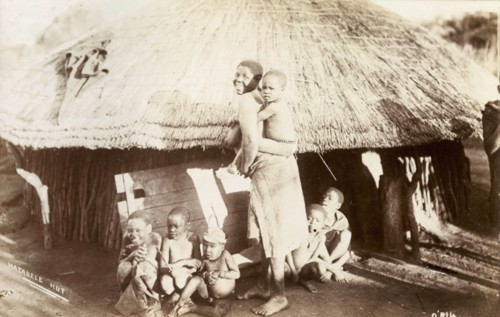 A Matabele family. A Matabele (Ndebele) woman turns to smile for the camera, a young child clinging