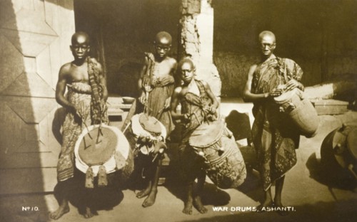 Asante drummers. Three Asante (Ashanti) boys and an adult male pose for the camera holding drums.