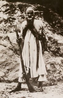 An elderly sniper. Portrait of an elderly man, possibly an Afridi, armed with a rifle and sword.