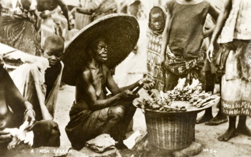 Fish seller, Gold Coast. An elderly woman dressed in a huge, wide brimmed hat, sells fish to