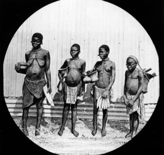 Four African women. Group portrait of four semi-naked women, each carrying a basket filled with