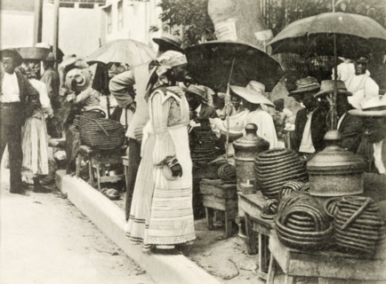Selling jackass rope tobacco. A line of street traders sit beneath umbrellas as they sell rolls of