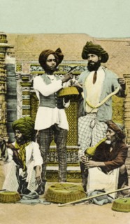 Snake charmers, India. A posed portrait of four Indian snake charmers. The man pictured kneeling to