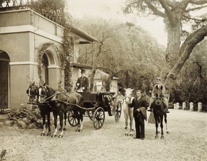 Horses at the ready. Servants wait with horses at the ready in the driveway to a large colonial