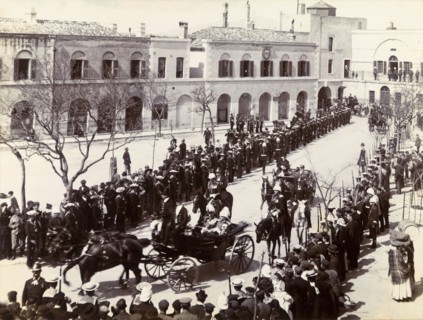 Procession in Gibraltar. Two distinguished gentlemen are driven through crowds gathered in a town