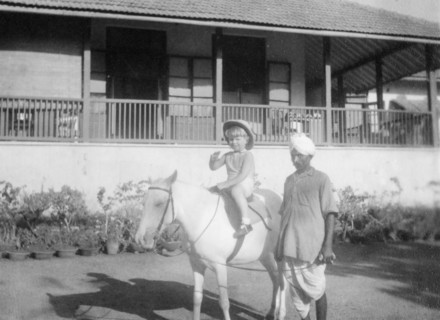 Adam rides a pony, Bombay. A British boy called Adam waves to the camera as he rides a pony in the