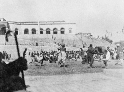 Wrestling match in Sukkur. A number of wrestlers fight each other in front of seated spectators