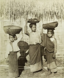 Three Burmese girls at Wuntho. Three young Burmese girls pose outside a thatched dwelling,