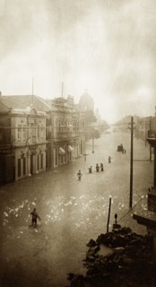Flooded street in Karachi. A small band of people wades towards a partially submerged vehicle along