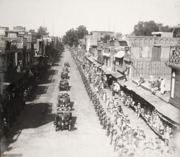 Indian Army officers salute a procession of cars. Hundreds of Indian Army officers, and crowds of
