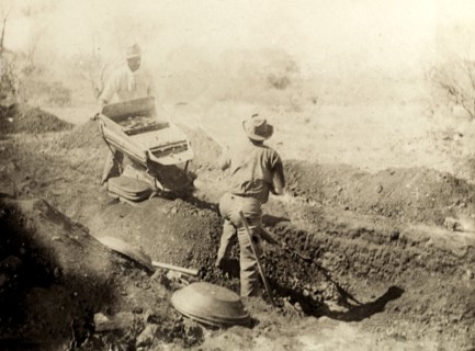 Digging for gold at Kalgoorlie. Two miners dig for gold in the outback: one man shovels earth from