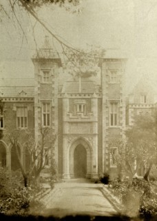 Front entrance of Government House, Perth. A wide path, flanked by trees, leads up to an arched