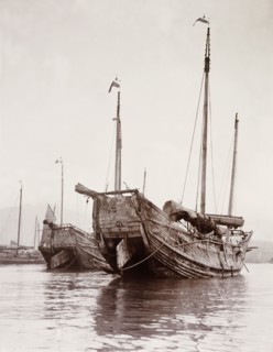 Junks moored at a Hong Kong harbour. Two Chinese junks are moored at a Hong Kong harbour with their