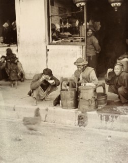 A meal by the wayside', Hong Kong. A Chinese street trader distributes food from a wooden bucket by