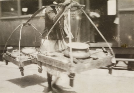 Burmese hawker at a railway station. A Burmese hawker attempts to sell his wares to passers-by at a