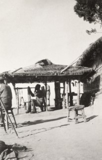 On watch at 'Pagoda Hill'. A Burmese man dressed in military uniform and a fez hat sits on a stool