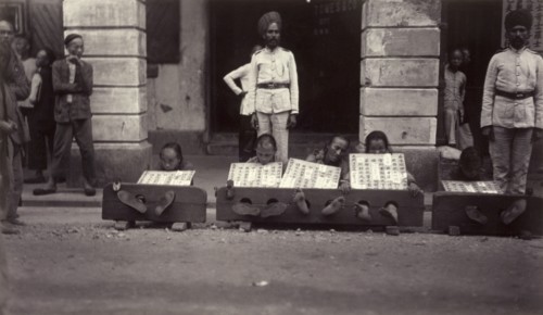 Petty criminals in the stocks, Hong Kong. A group of petty criminals sit with their ankles