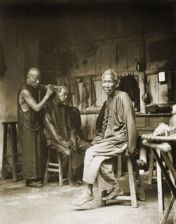 Ear cleaning at a barber's shop, China. A man sits on a stool to have his ears cleaned at a