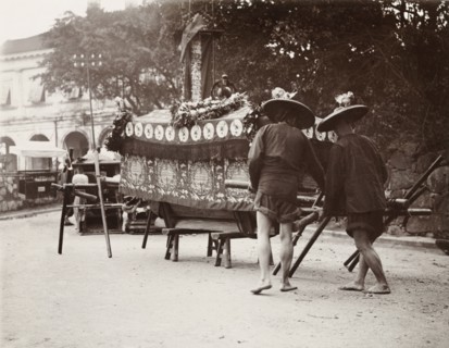 Pallbearers at a Chinese funeral. Two pallbearers prepare to carry a coffin on a wooden bier during