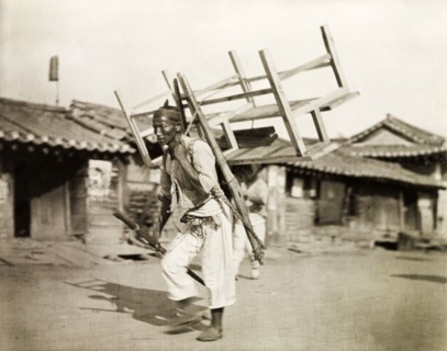A Korean labourer carries a bench. A Korean labourer carries a wooden bench strapped to his back