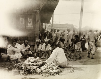 Vegetable stall at an outdoor market in Seoul. A street trader wearing a 'gat' (a traditional