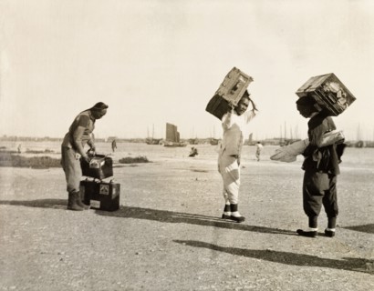 Luggage handlers at Newchwang port. Three luggage handlers prepare to load suitcases onto a waiting