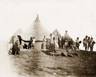 Matabele men at Cecil Rhodes' farm. Matabele (Ndebele) men mill about beside a cluster of thatched