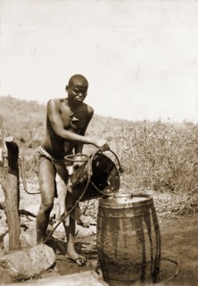 Collecting water at a village well. A Matabele (Ndebele) man pours water from a bucket into a