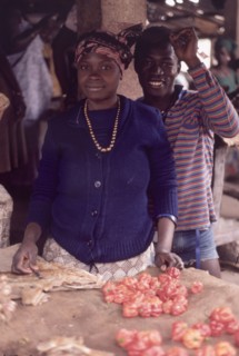 Preparing food at Bakau market. An African man and woman smile for the camera as they prepare food