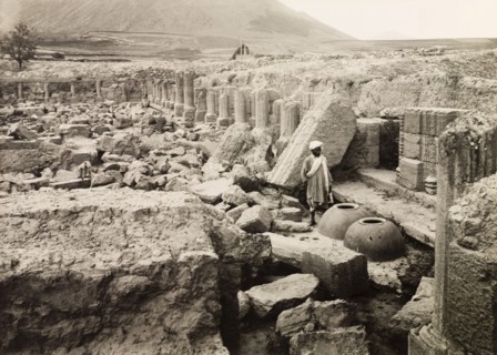 Avantisvami Temple at Avantipur. A man stands by two large clay pots amidst the ruins of