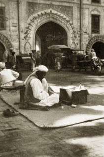 Letter-writing service. A street trader offering a letter-writing service sits on a rug on the
