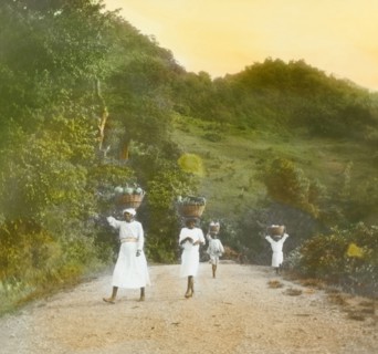 Transporting breadfruit in St Vincent. Women and children carry breadfruit along a country road in