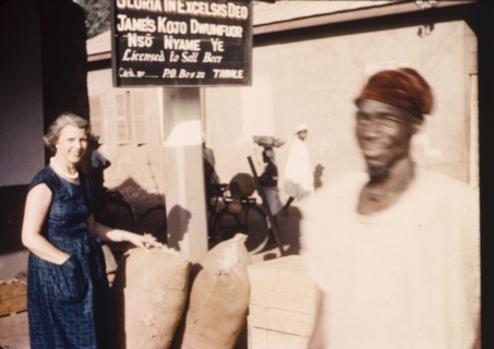 Street trader's stall in Tamale. A European woman inspects sacks at a street traders stall beneath